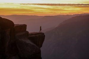 A person standing on the edge of a cliff at daytime