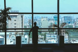 Silhouette of a person standing in front of wide glass windows