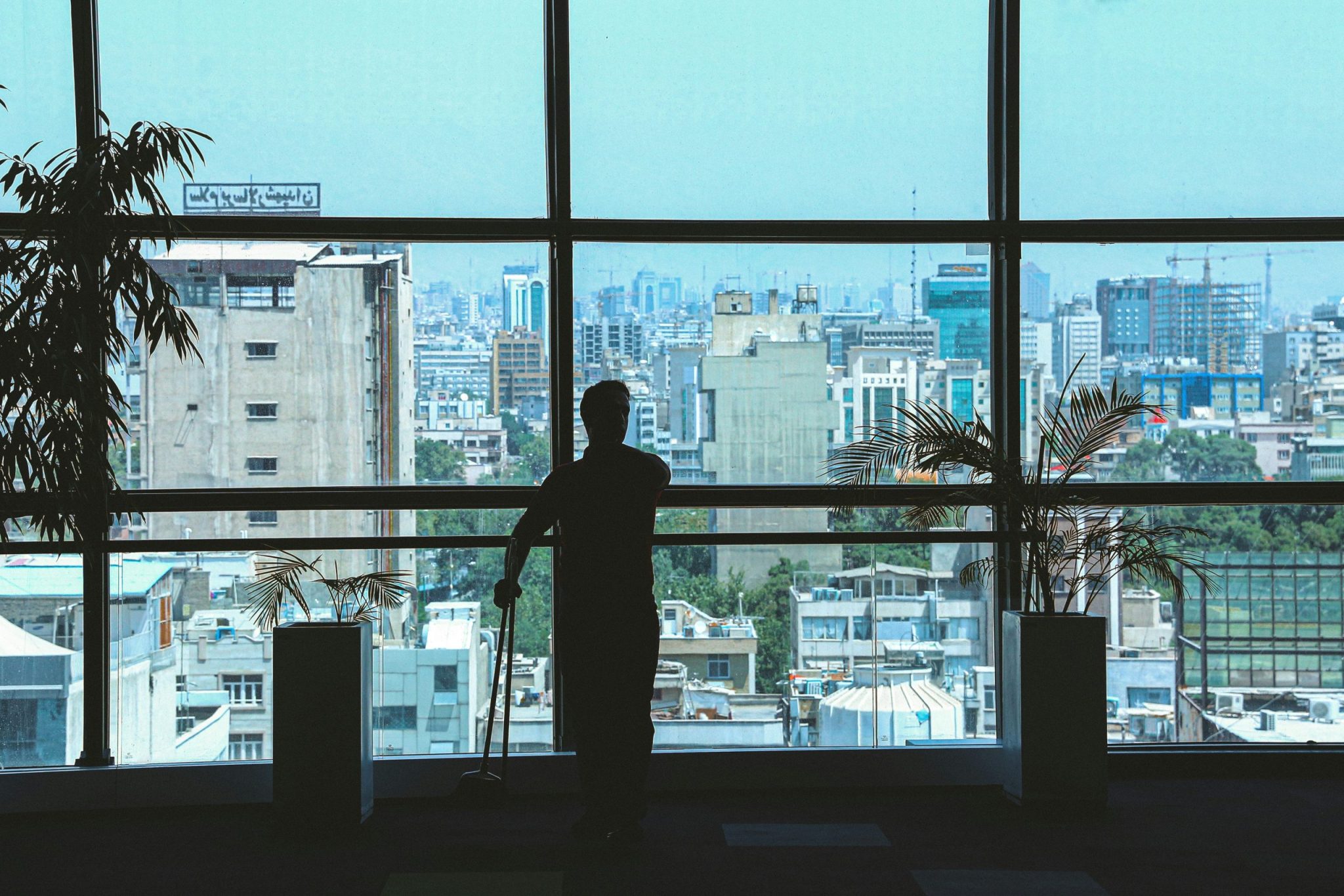 Silhouette of a person standing in front of wide glass windows
