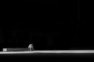 Grayscale photo of a man sitting on a concrete bench