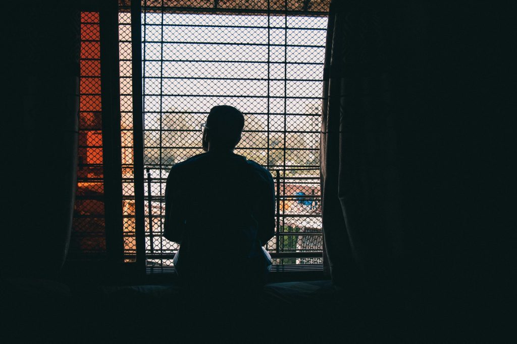Silhouette of a man staring out on a window