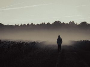 Person standing on a dirt road in the middle of a field