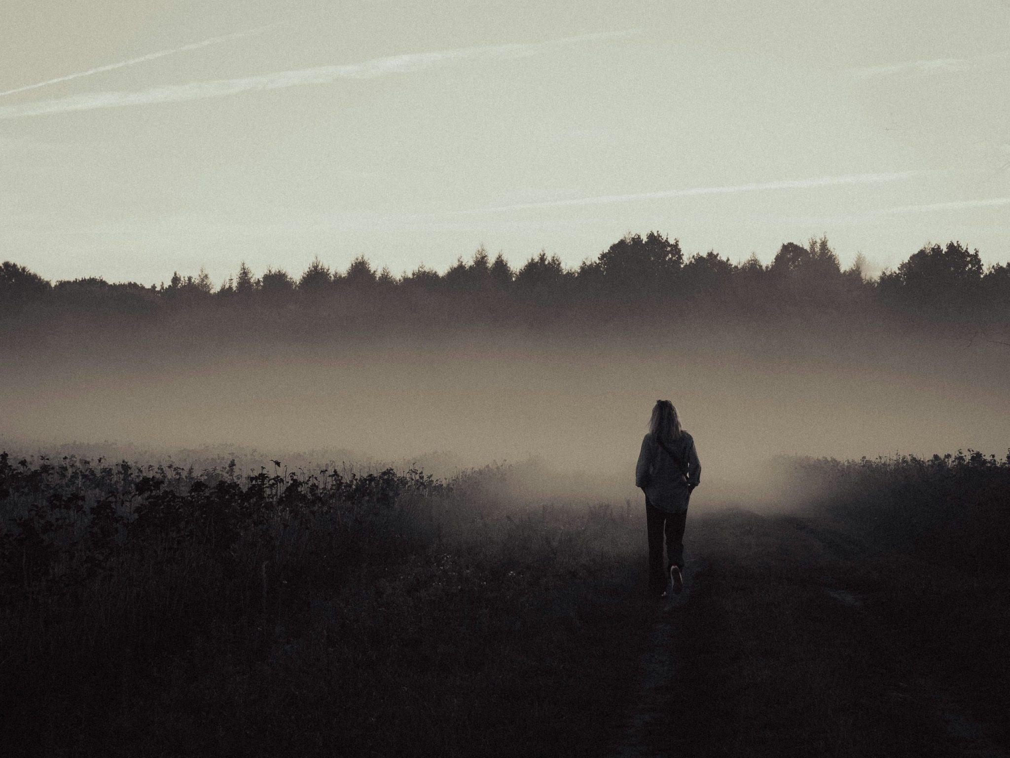 Person standing on a dirt road in the middle of a field