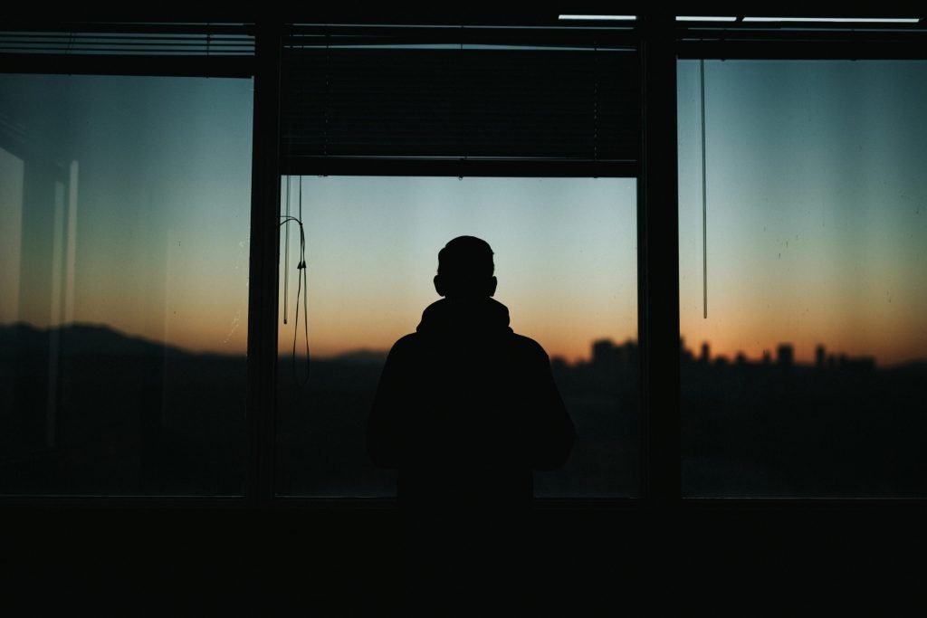 Silhouette of a man looking out an office window at sunset