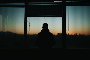 Silhouette of a man looking out an office window at sunset