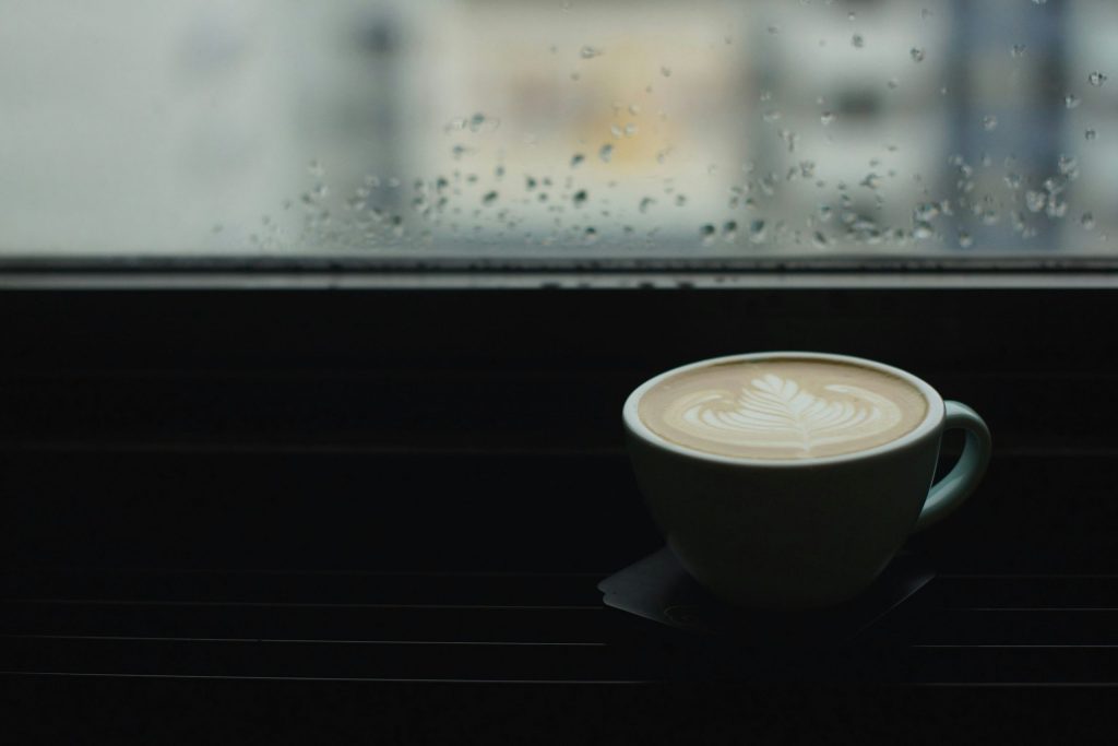 Ceramic cup with coffee on saucer on a table by the window