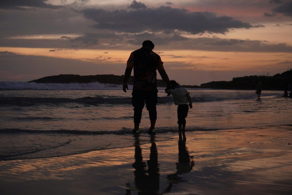 Silhouette of a father and child on a beach at sunset
