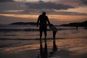 Silhouette of a father and child on a beach at sunset