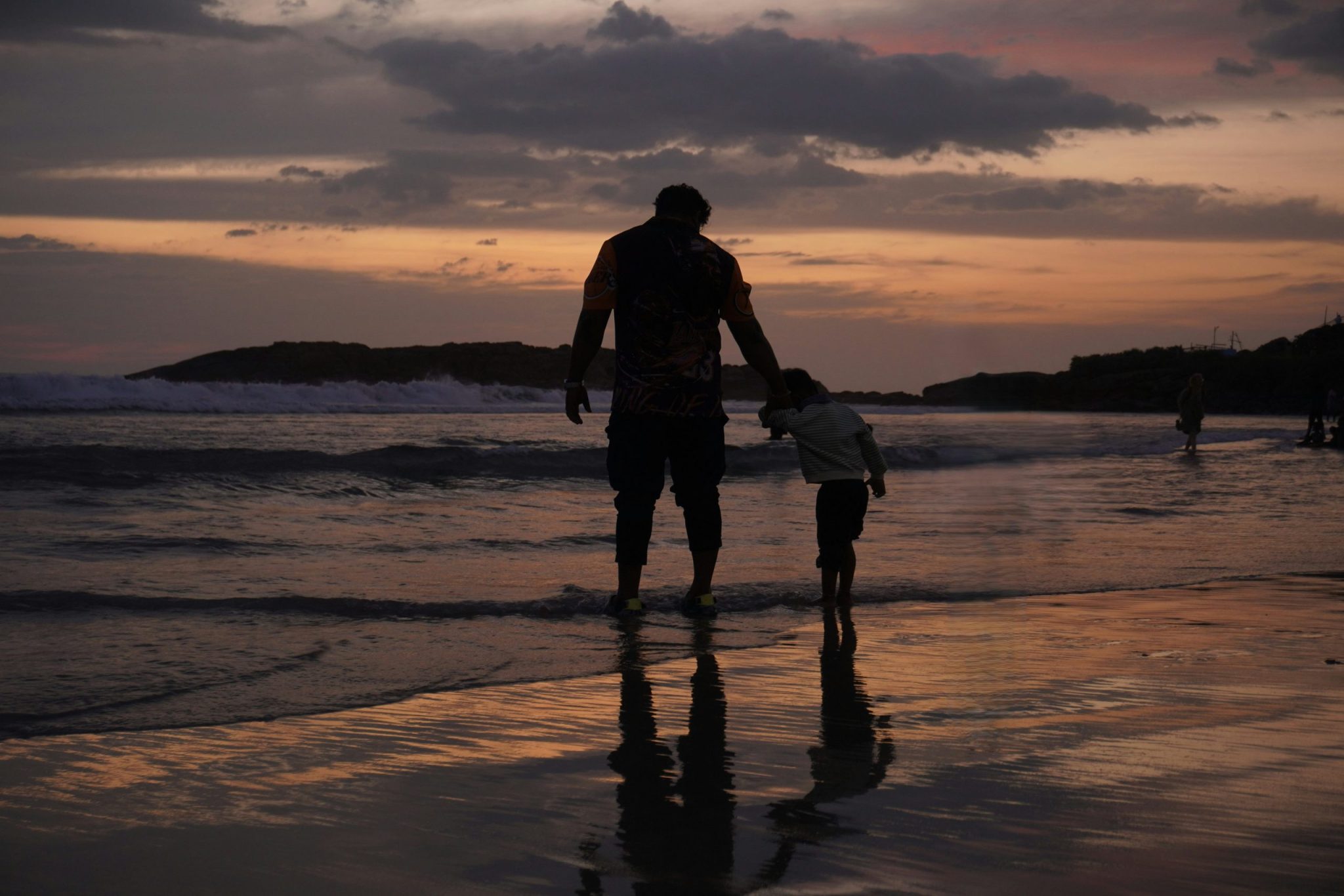 Silhouette of a father and child on a beach at sunset