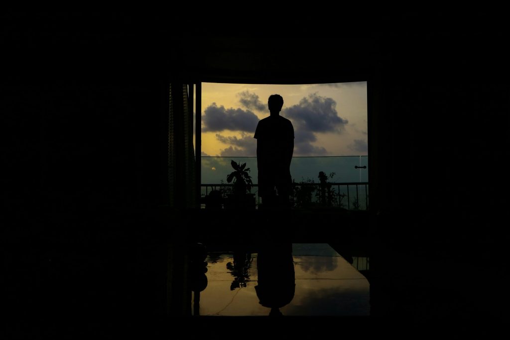 Silhouette of a man standing in front of a large open window