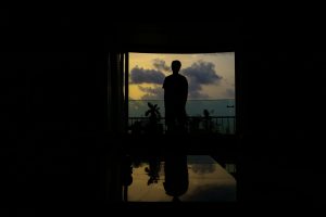Silhouette of a man standing in front of a large open window