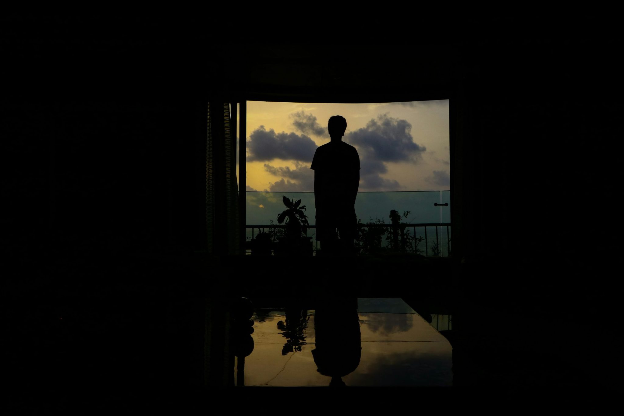 Silhouette of a man standing in front of a large open window