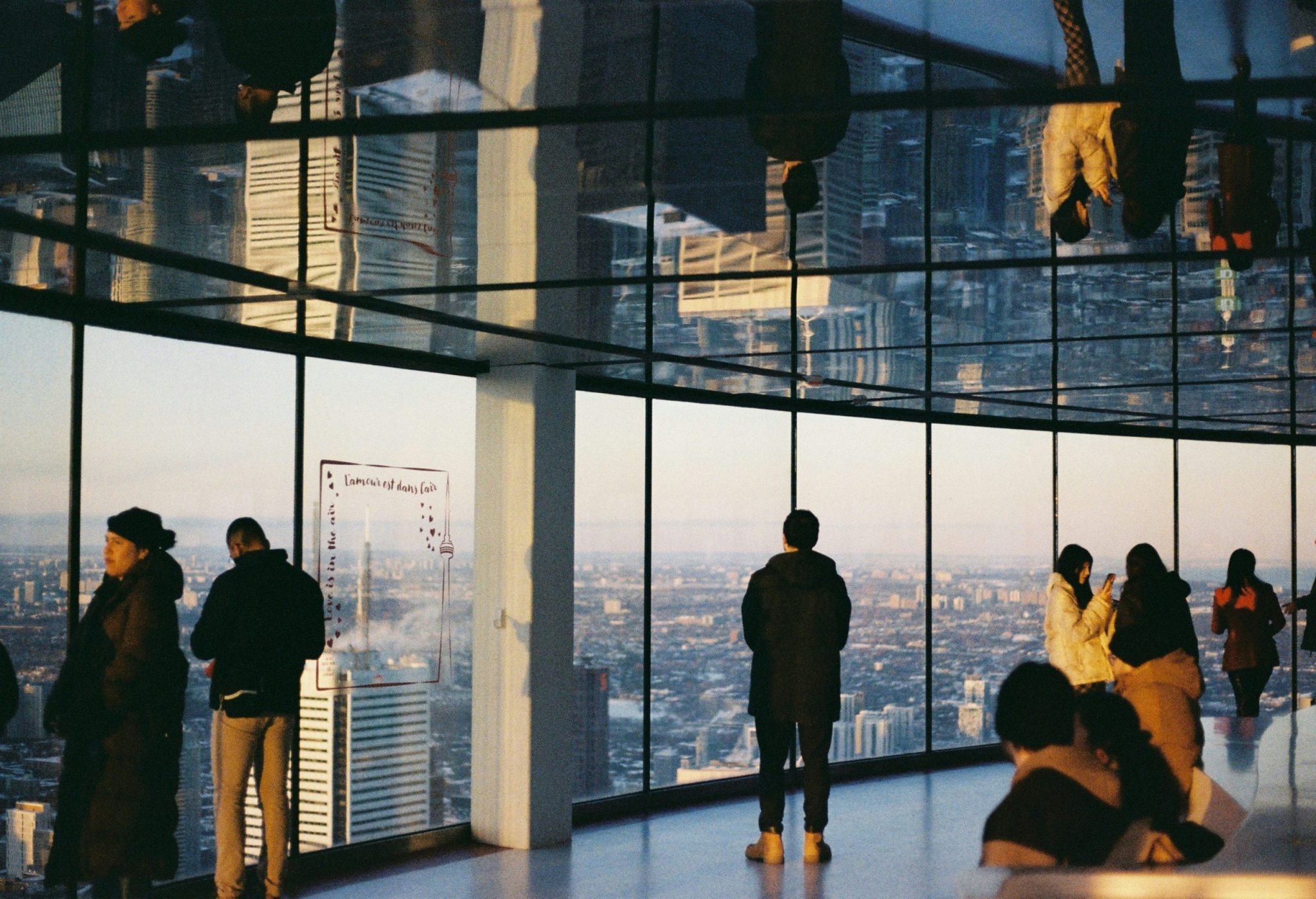 Photo of people admiring the city view through the wide glass window of a building